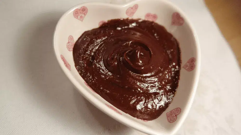 Pâte à tartiner vegan choco-noisette avec cuillère en bois dans un bol en forme de coeur