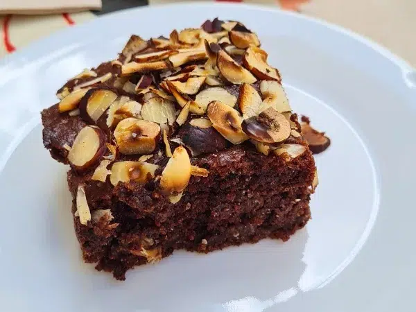 Brownie vegan et sans gluten avec amandes effilées sur une assiette blanche