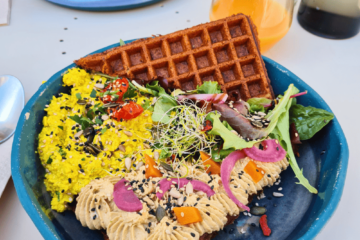 Assiette végétale colorée avec une gaufre du houmous et de la salade