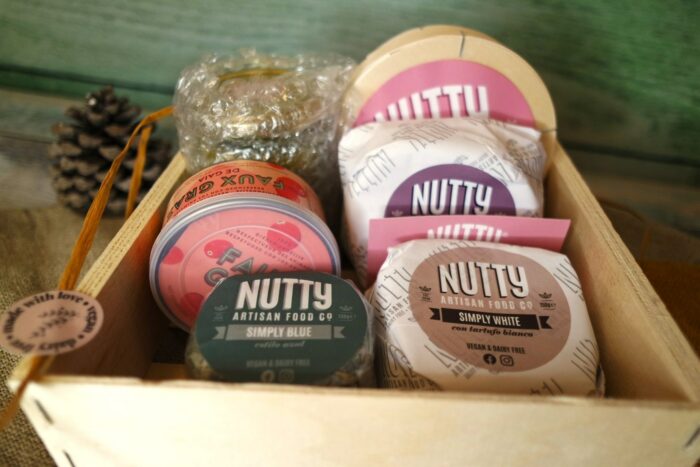 Fromages vegans espagnol dans une boîte en carton Nutty Artisan Food avec pomme de pin en fond