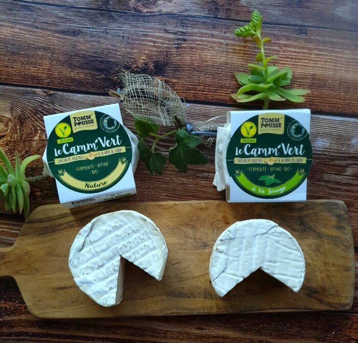 Fromages vegan Le Camm'Vert de Tomm'Pousse coupé sur planche en bois avec plantes grasses. 