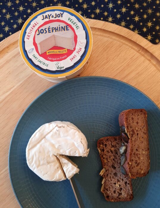 Camembert vegan Jay & Joy Joséphine sur une assiette avec deux tranches de pain sans gluten avec packaging dans le fond de la photo