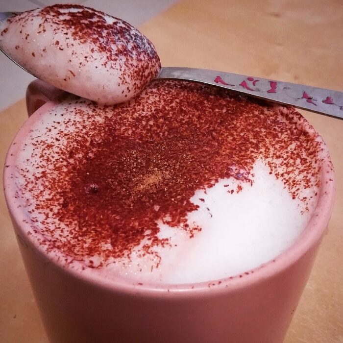 Tasse rose avec une mousse généreuse saupoudré de cacao et de cannelle