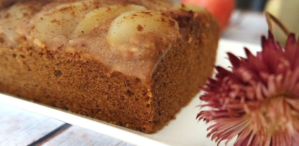 Gâteau aux pommes sur une assiette blanche avec une fleur séchée