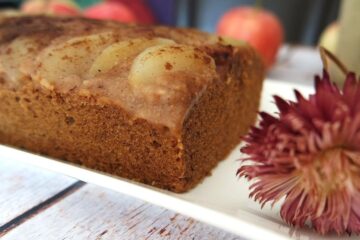 Gâteau aux pommes sur une assiette blanche avec une fleur séchée