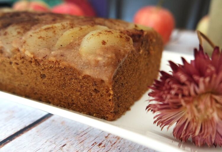 Gâteau aux pommes sur une assiette blanche avec une fleur séchée