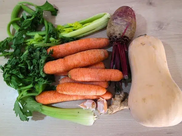 légumes sur le plan de travail: carottes, courge butternut, betterave, branches de céleri