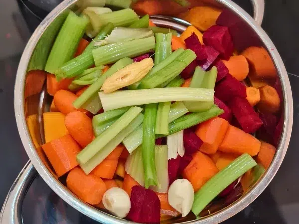 légumes verts, oranges et rouges découpés et posés dans le tamis du vitaliseur de Marion