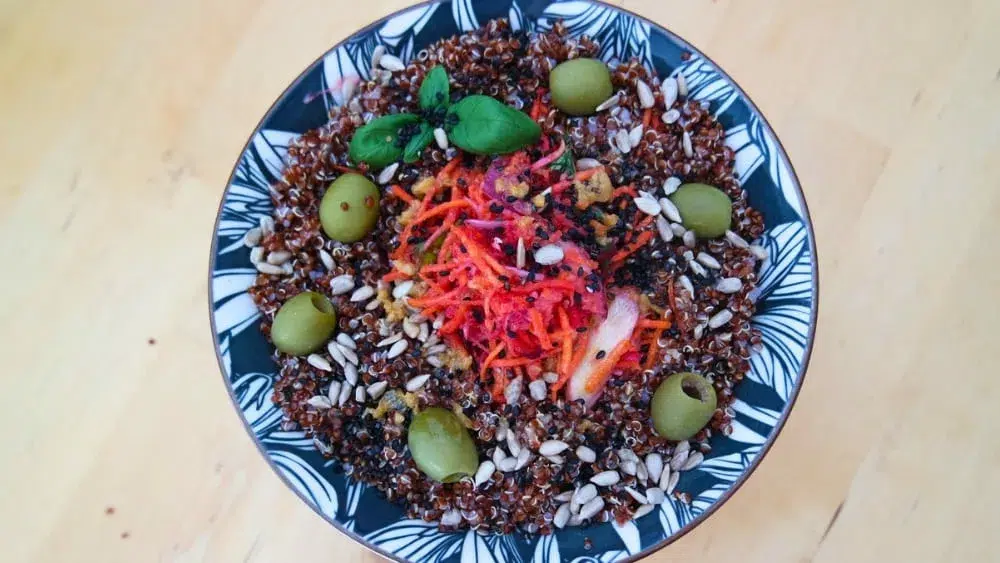 Assiette avec quinoa rouge, carottes râpées, olives vertes
