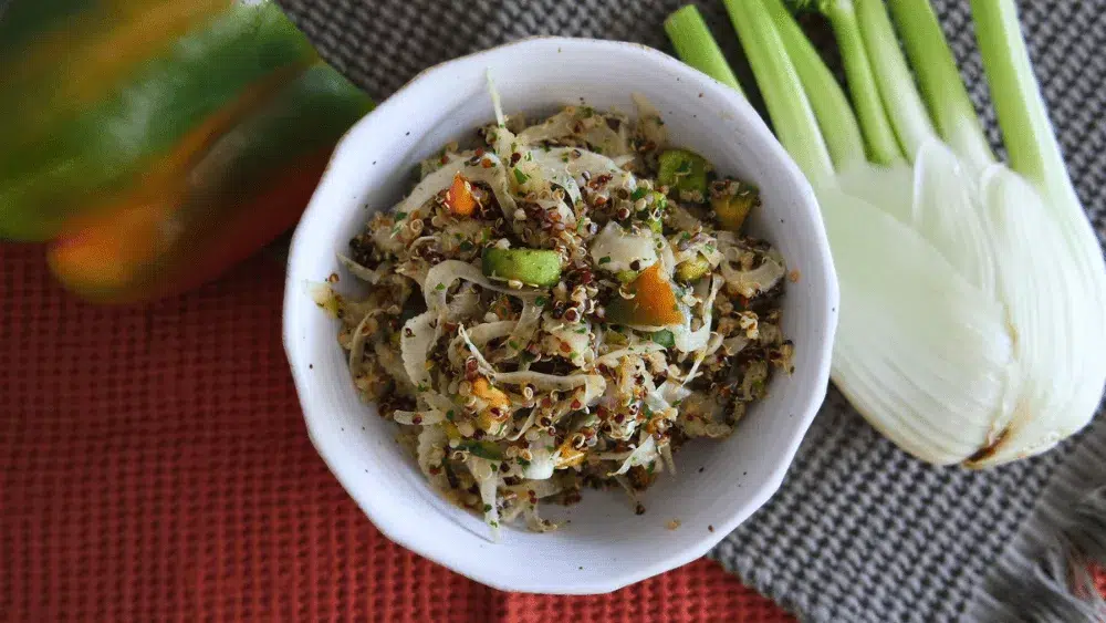 Salade de quinoa fenouil et poivron dans un bol blanc avec torchon rouge nid d'abeille et fenouil