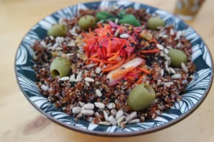 Assiette avec quinoa rouge, carottes râpées, olives vertes